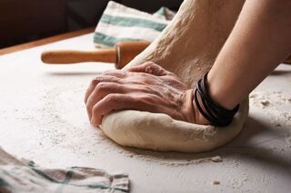 hands kneading dough on a white surface