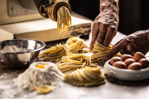 Hands of a chef twisting fettuccine pasta into nests after making a fresh dough from the ingredients